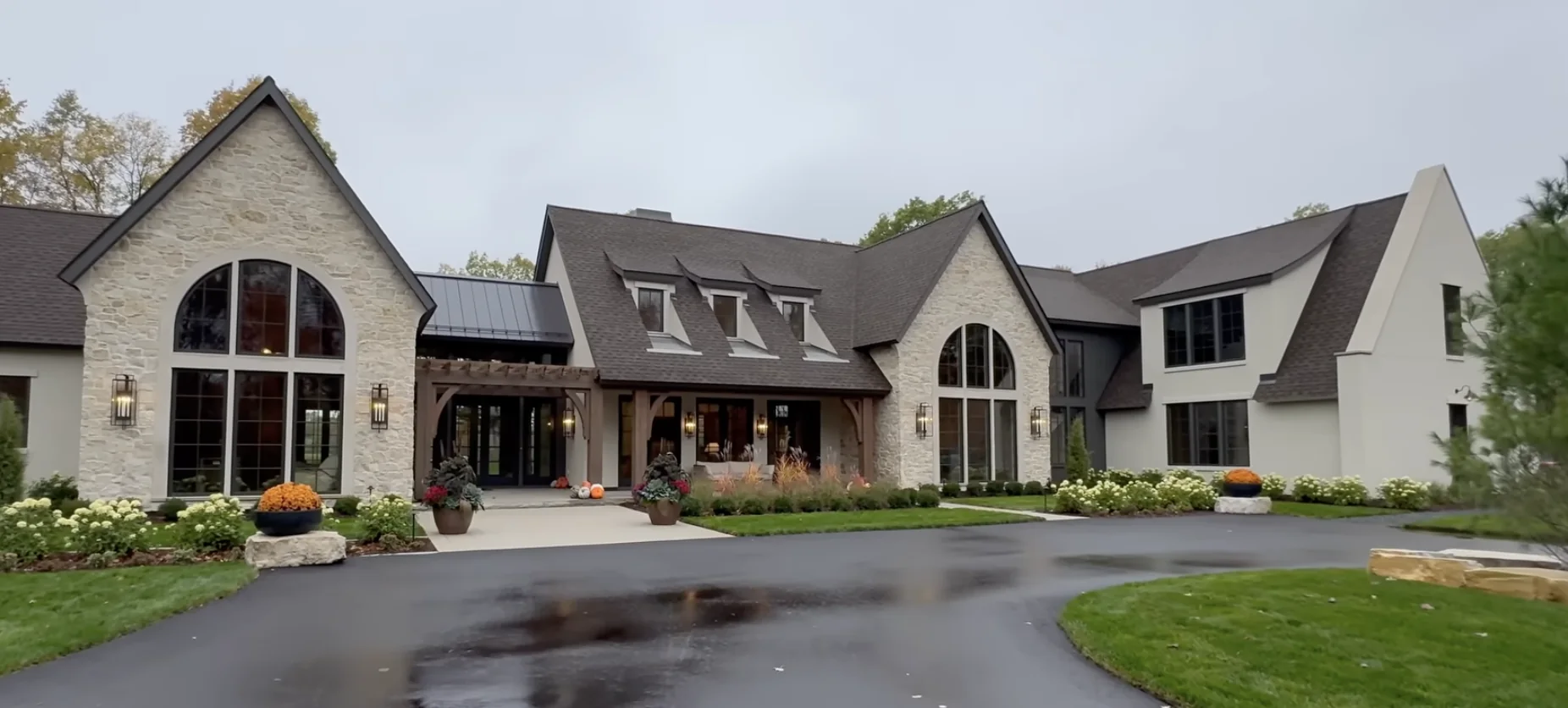 Stone estate house with complex pitched roofs and deep covered porches